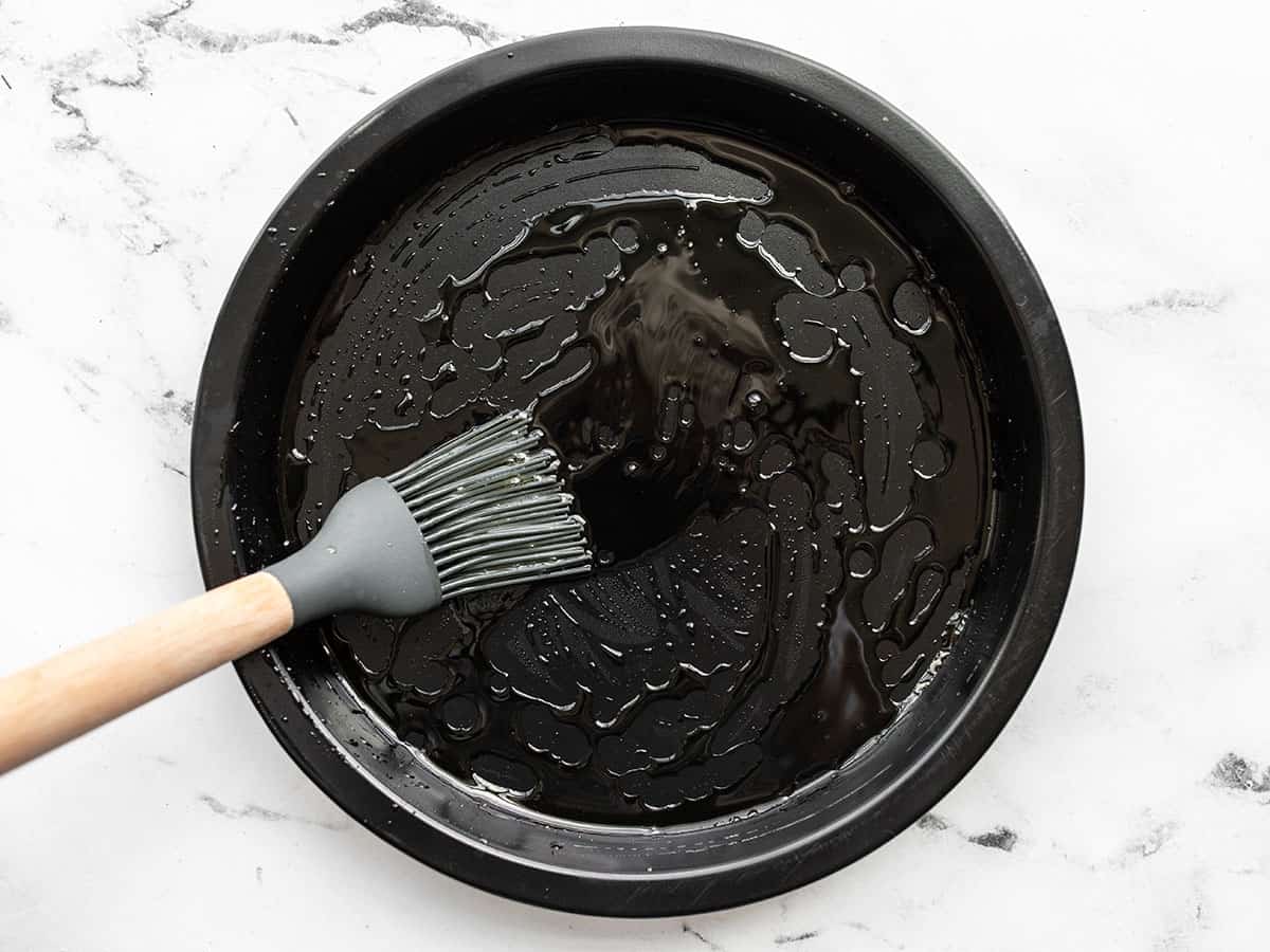 Oil being brushed onto a round bakign dish