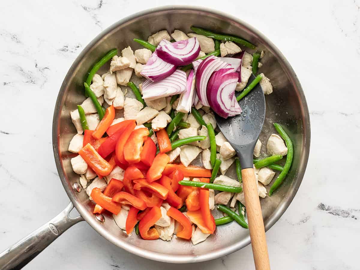 Red bell pepper and red onion added to the skillet