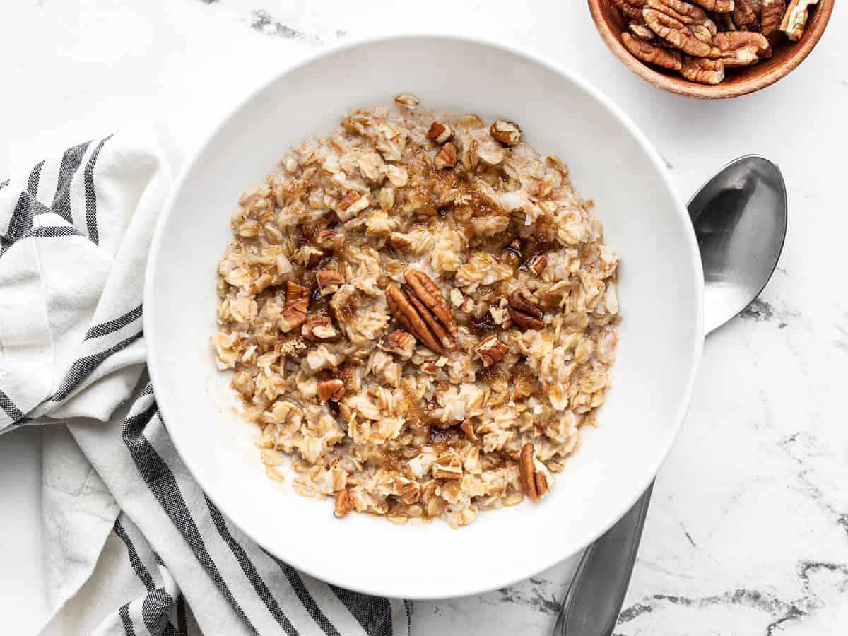 Finished cinnamon pecan cauli oats in a bowl with a spoon on the side