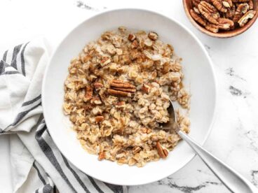 Overhead view of a bowl full of cinnamon pecan cauli oats with a spoon in the center