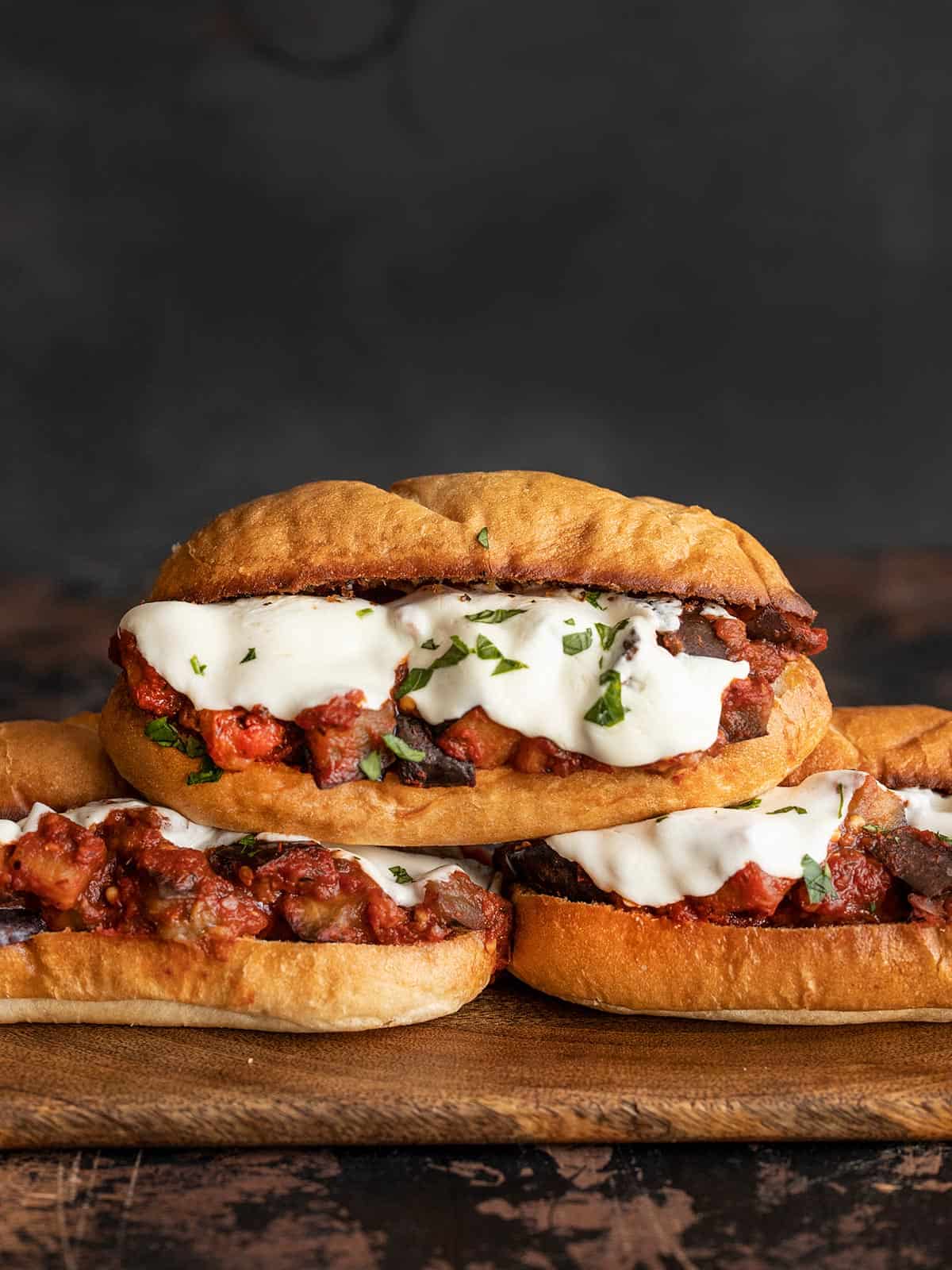 Three Eggplant Mozzarella Sandwiches on a wooden board