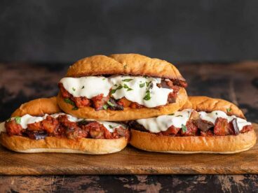 three stacked eggplant mozzarella sandwiches on a wooden board