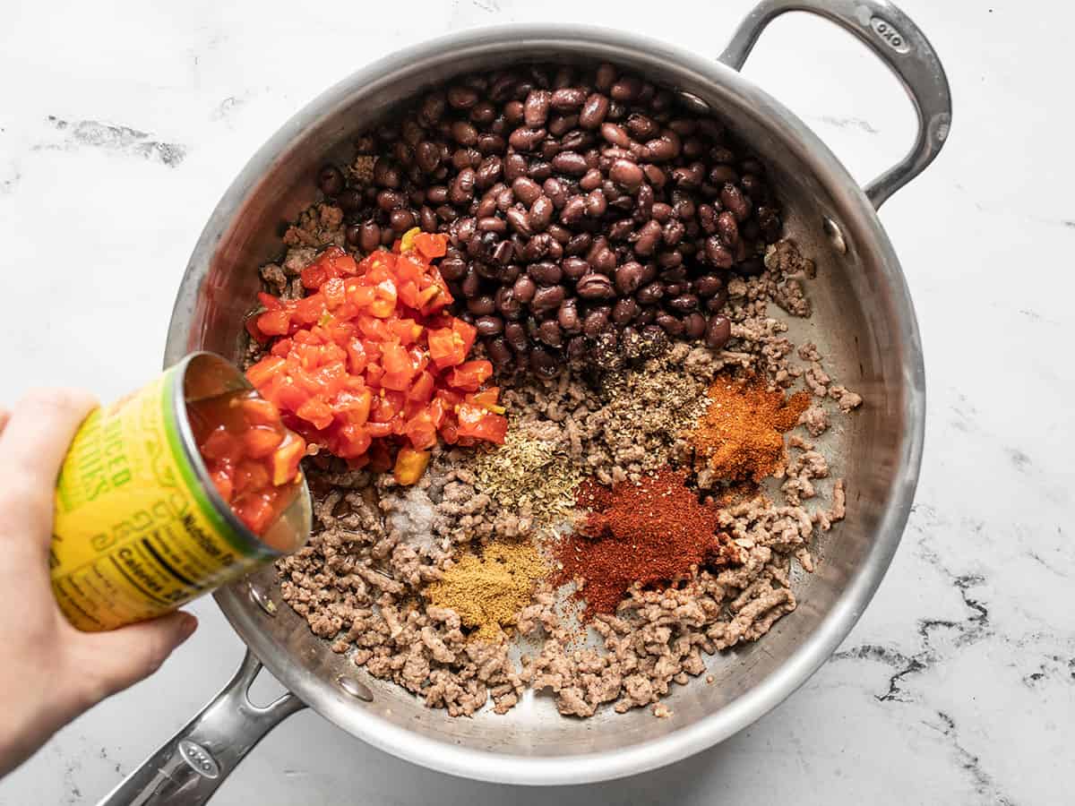 Tomatoes, beans, and seasoning added to the skillet