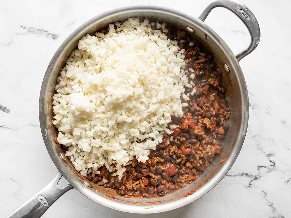 Frozen riced cauliflower added to the skillet.