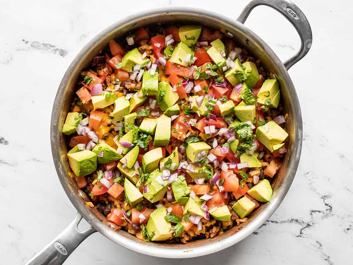 skillet topped with fresh tomato, avocado, red onion, and cilantro