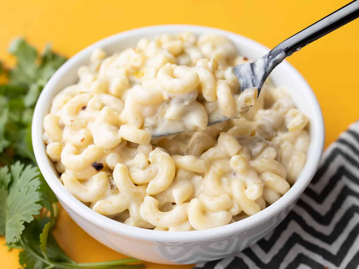 side view of a fork lifting green chile mac and cheese from the bowl