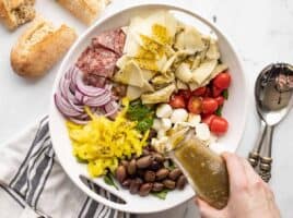 dressing being poured over the antipasto salad