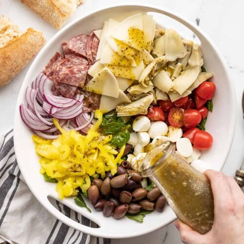 dressing being poured over the antipasto salad