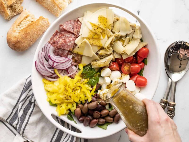 dressing being poured over the antipasto salad