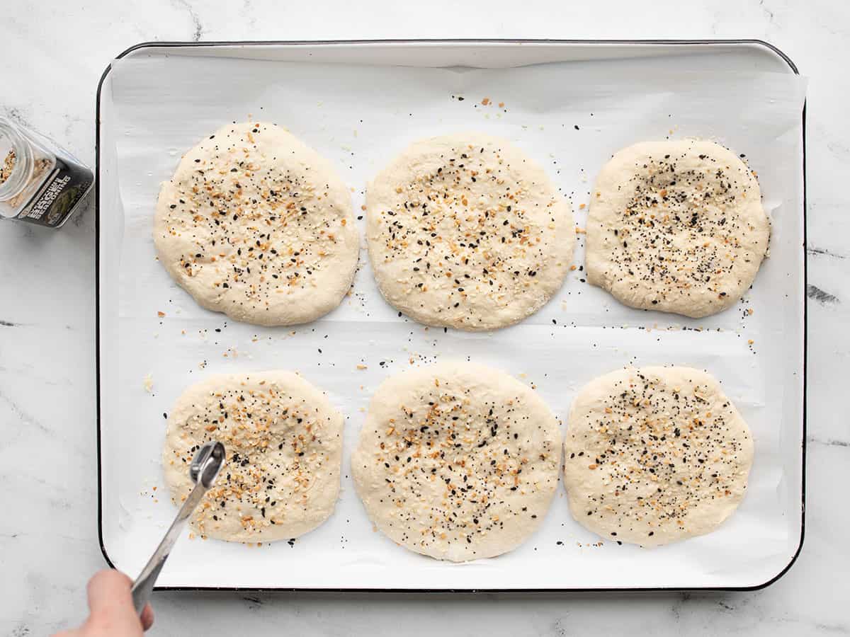 Seasoning being sprinkled on top of sandwich rounds