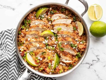 Chipotle lime chicken and rice in the skillet garnished with limes