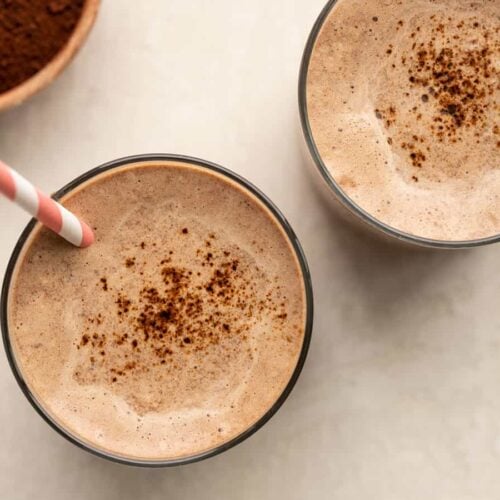 overhead view of two glasses full of chocolate coffee breakfast smoothie with straws