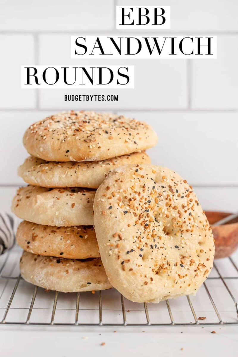 A stack of everything bagel sandwich rounds on a cooling rack, title text at the top