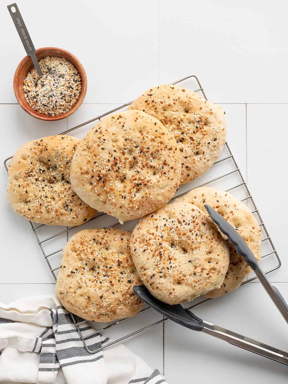 EBTB Sandwich Rounds on a cooling rack with tongs next to a bowl of seasoning