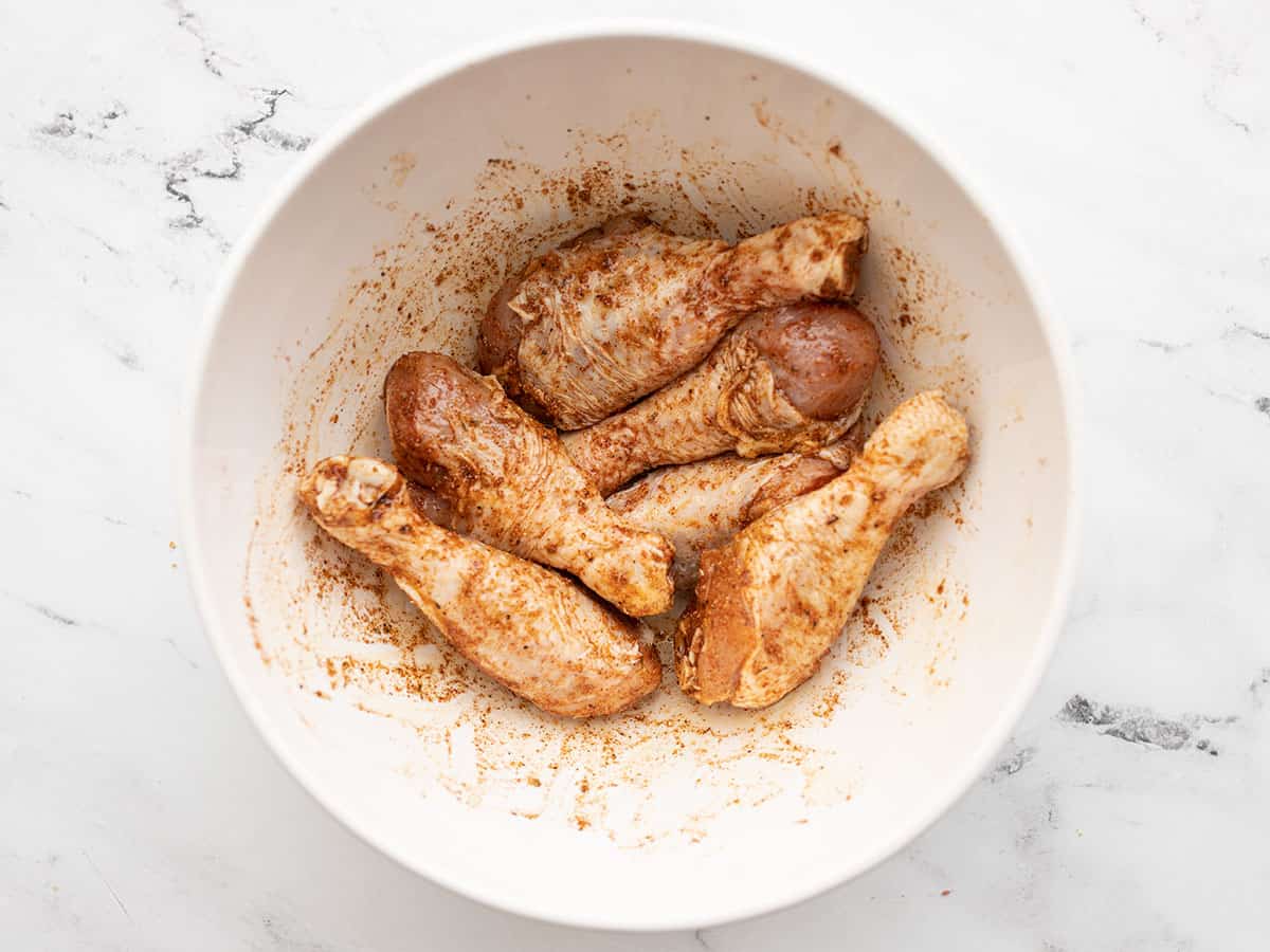 Seasoned chicken drumsticks in a bowl.