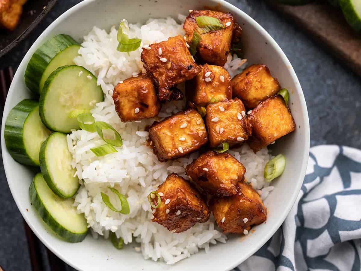 close up of honey sriracha tofu in a bowl with cucumber