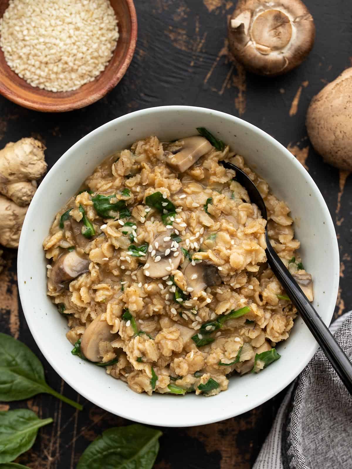 Overhead view of a bowl full of savory oatmeal with ingredients on the sides