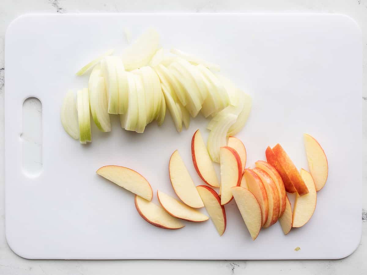 Sliced onion and apple on a cutting board