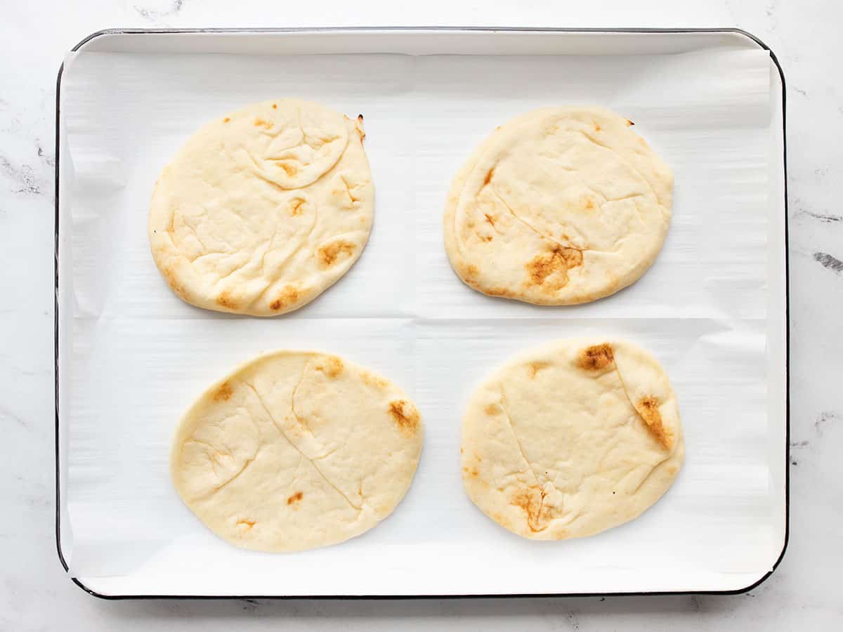 four naan on a parchment lined baking sheet