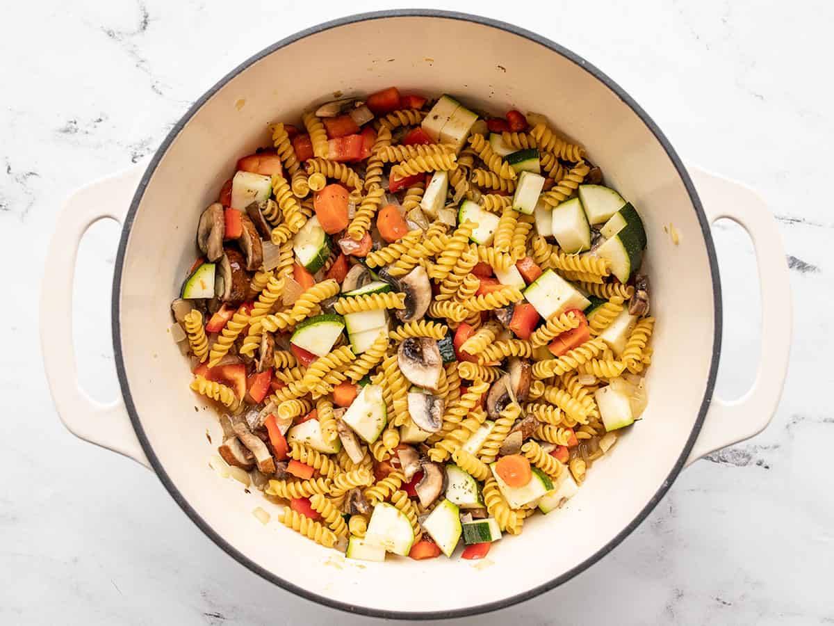 Stirred but uncooked pasta and vegetables in the pot