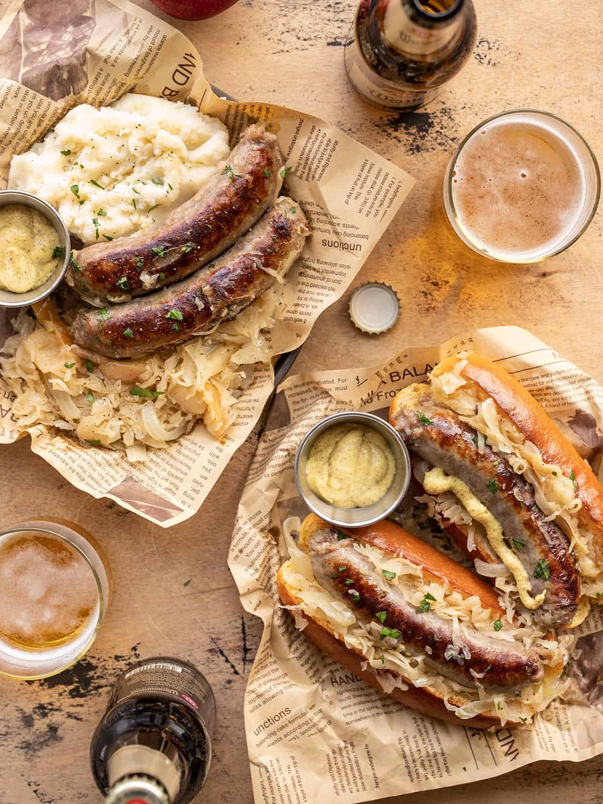 Bratwurst and Sauerkraut on two plates, one with buns and one with mashed potatoes