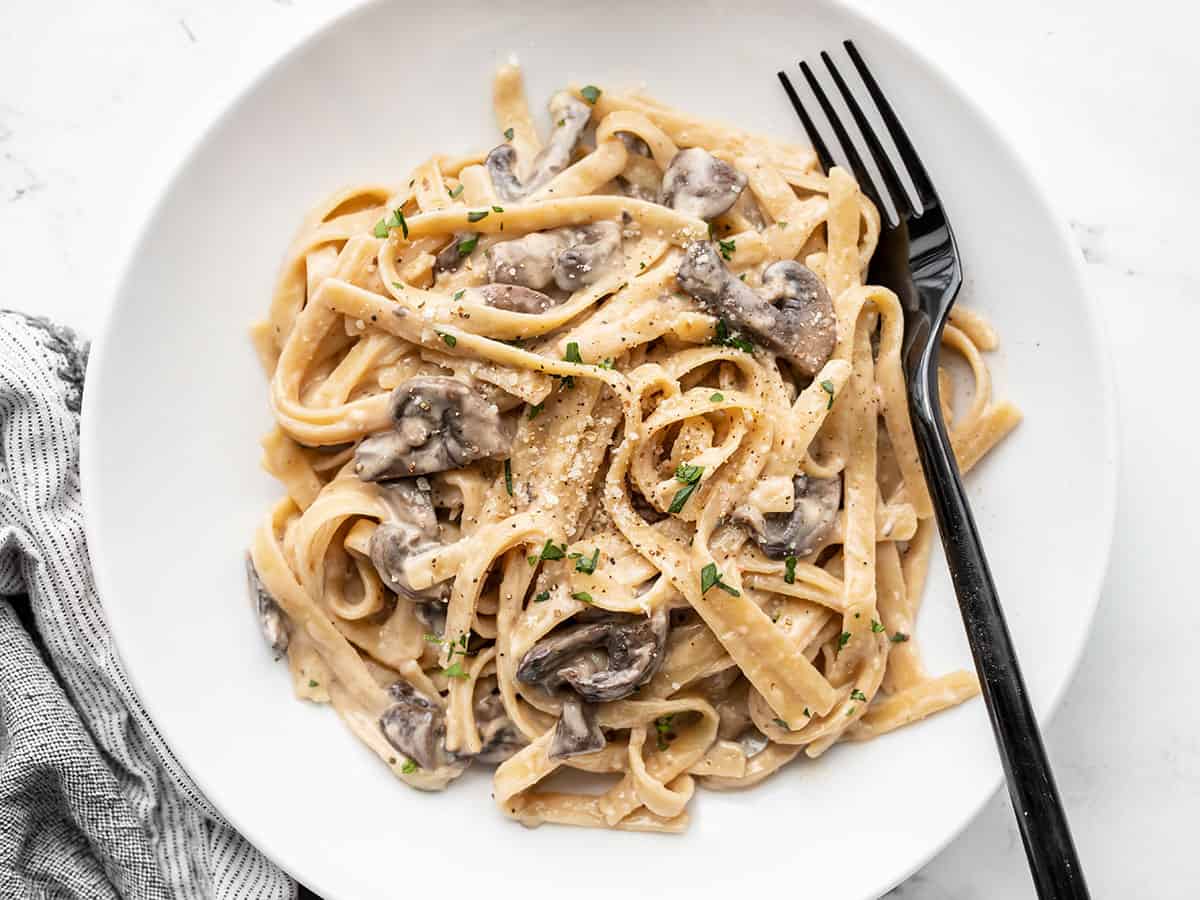 Overhead view of creamy mushroom pasta on a plate with a fork