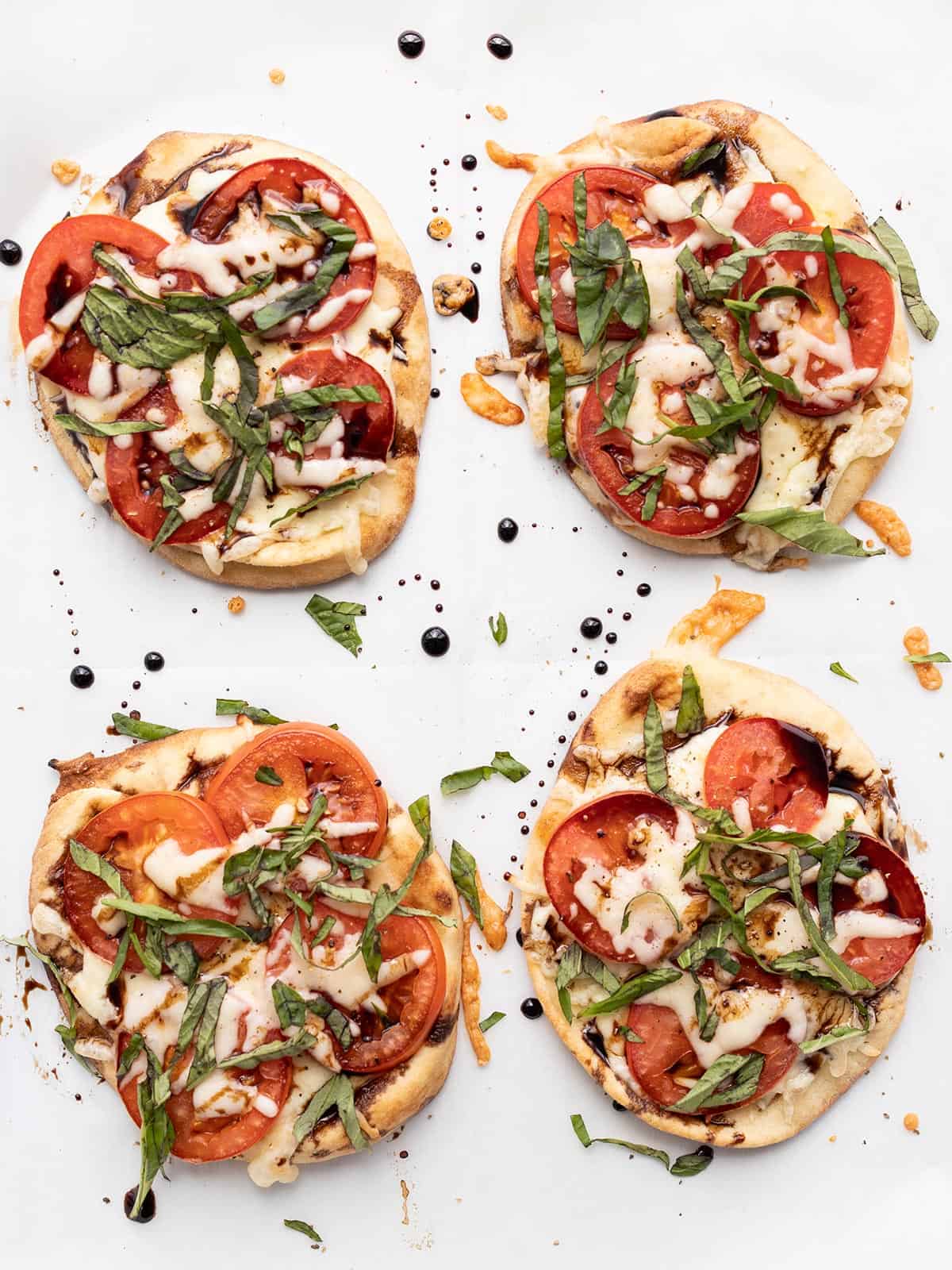 four mini caprese pizzas on a baking sheet