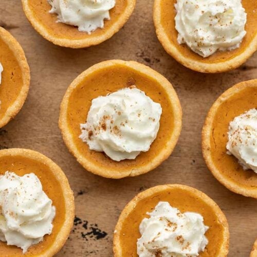 close up of mini pumpkin pies with whipped cream