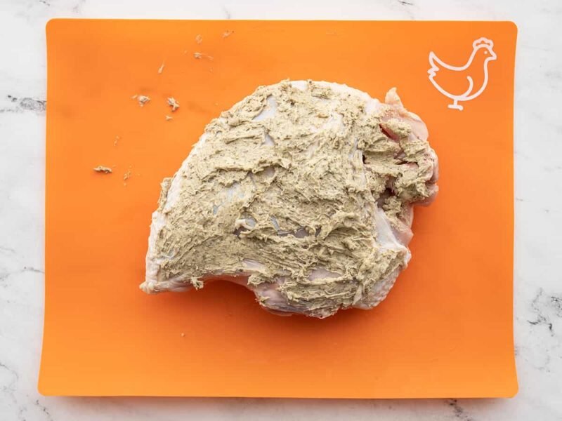 herb butter covered turkey breast on a cutting board