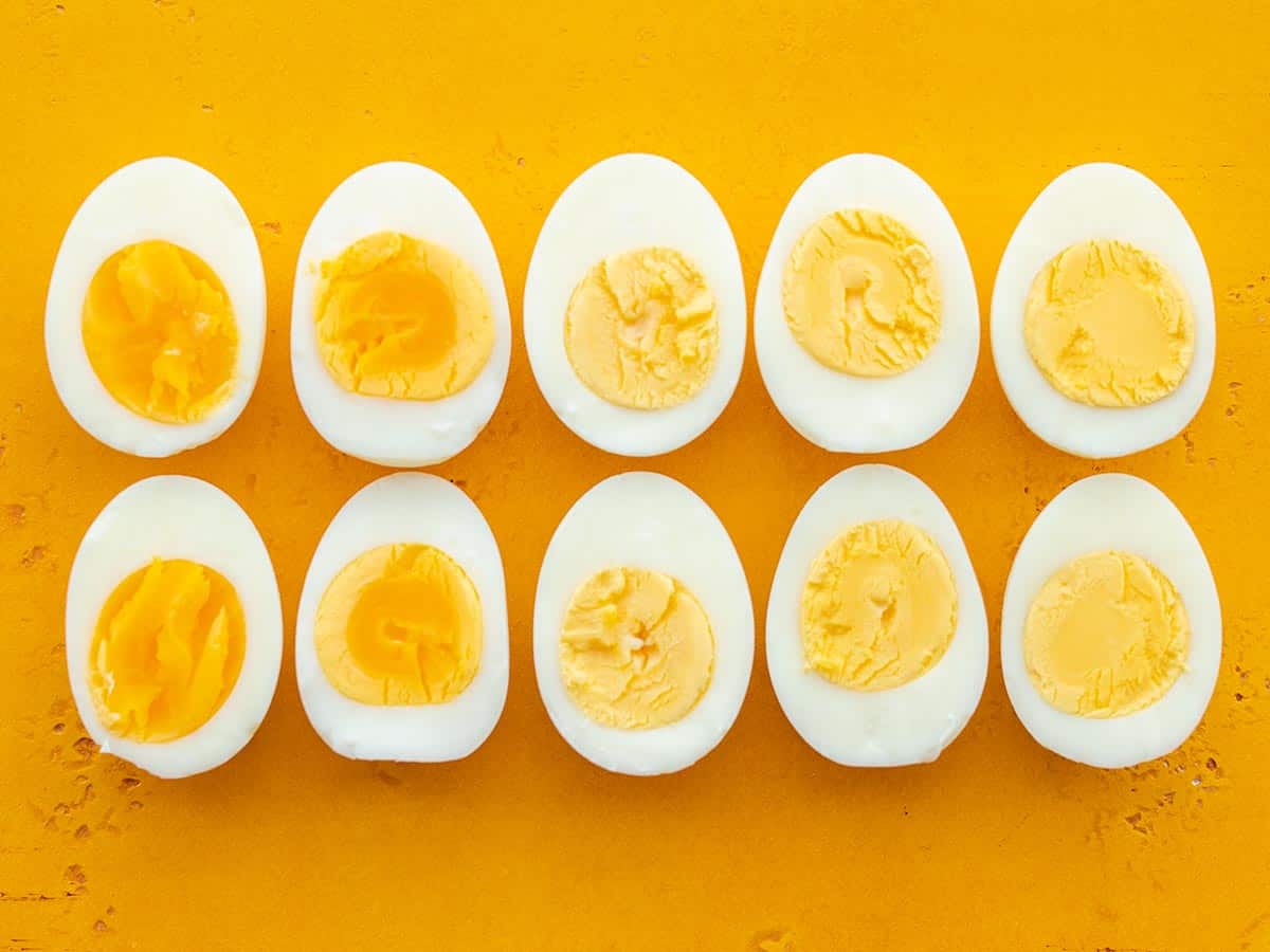 Hard boiled eggs lined up on a yellow background