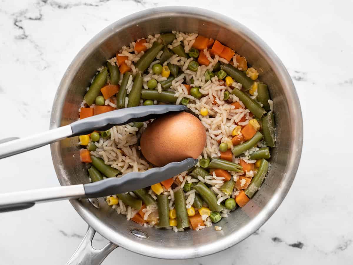 Egg being removed from the pot with cooked rice