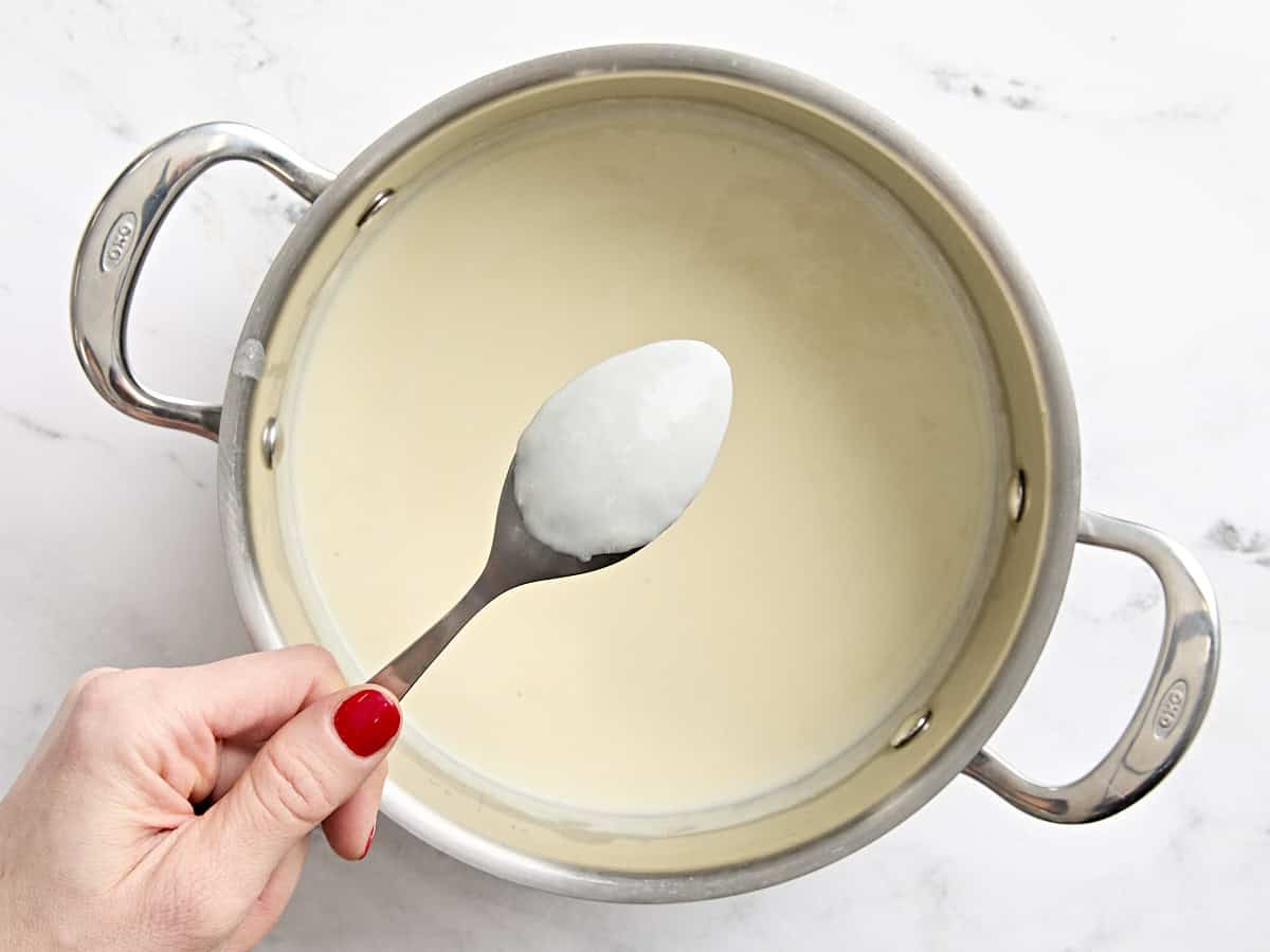 Mac and cheese sauce coating the back of a spoon.