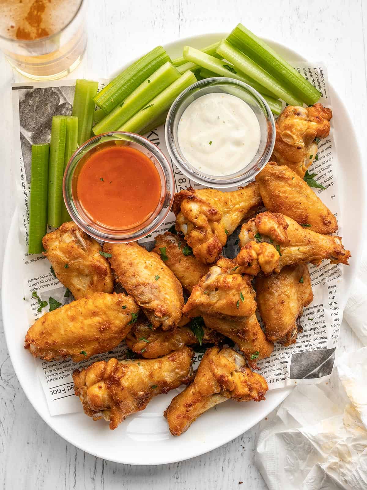 Close up of a platter of chicken wings with celery and sauces