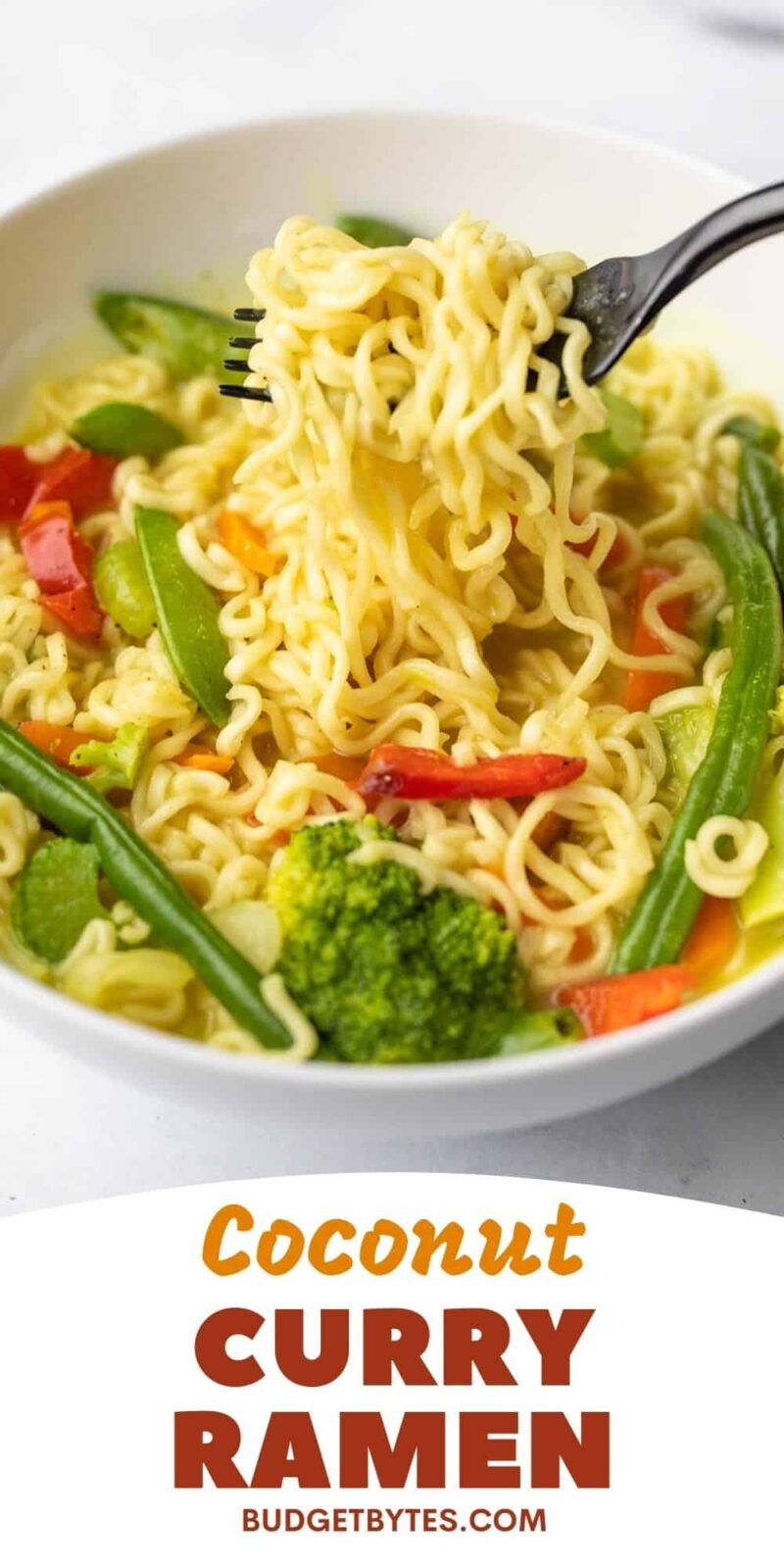 A fork lifting noodles from a bowl of coconut curry ramen