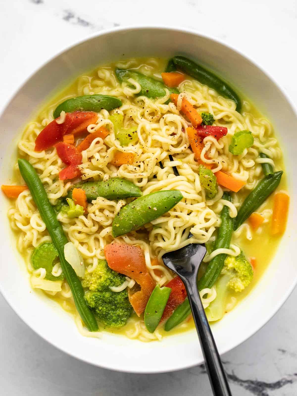 Close up of coconut curry ramen in the bowl with a fork