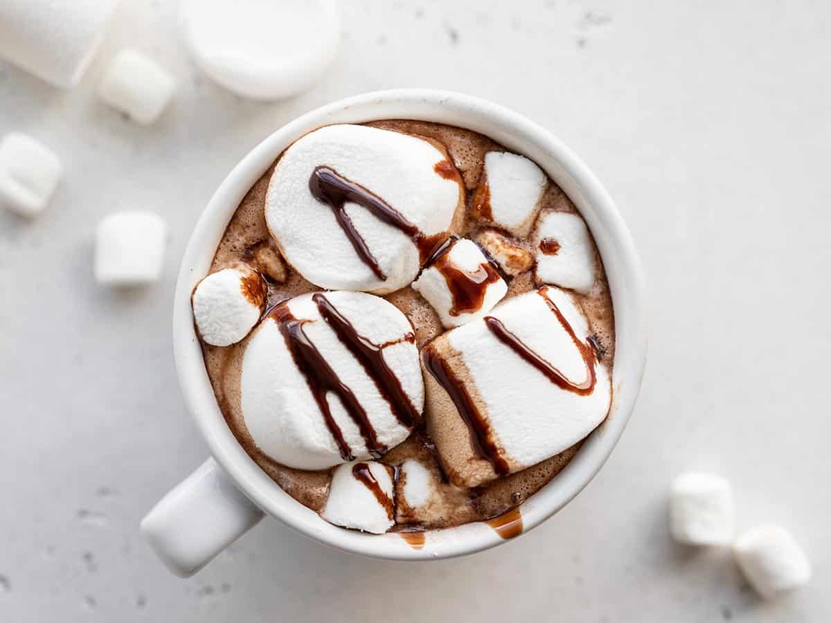 close up overhead view of a single mug of hot chocolate with marshmallows and chocolate syrup