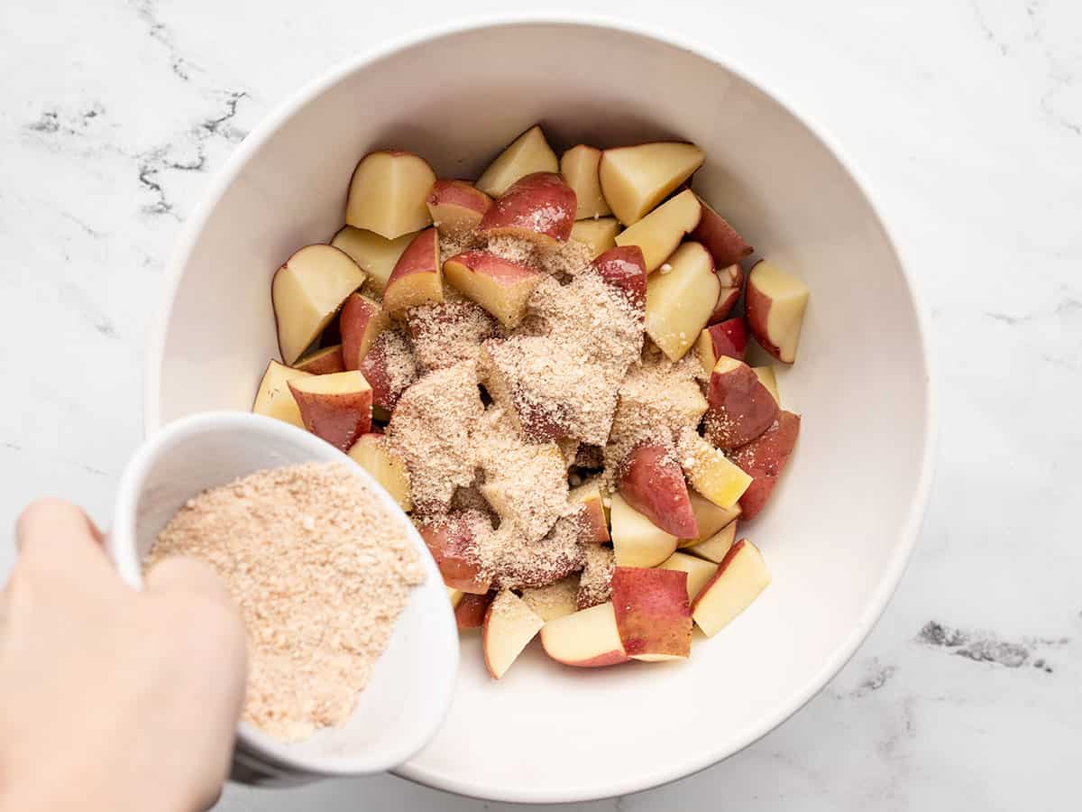 Seasoning being sprinkled over potatoes in the bowl