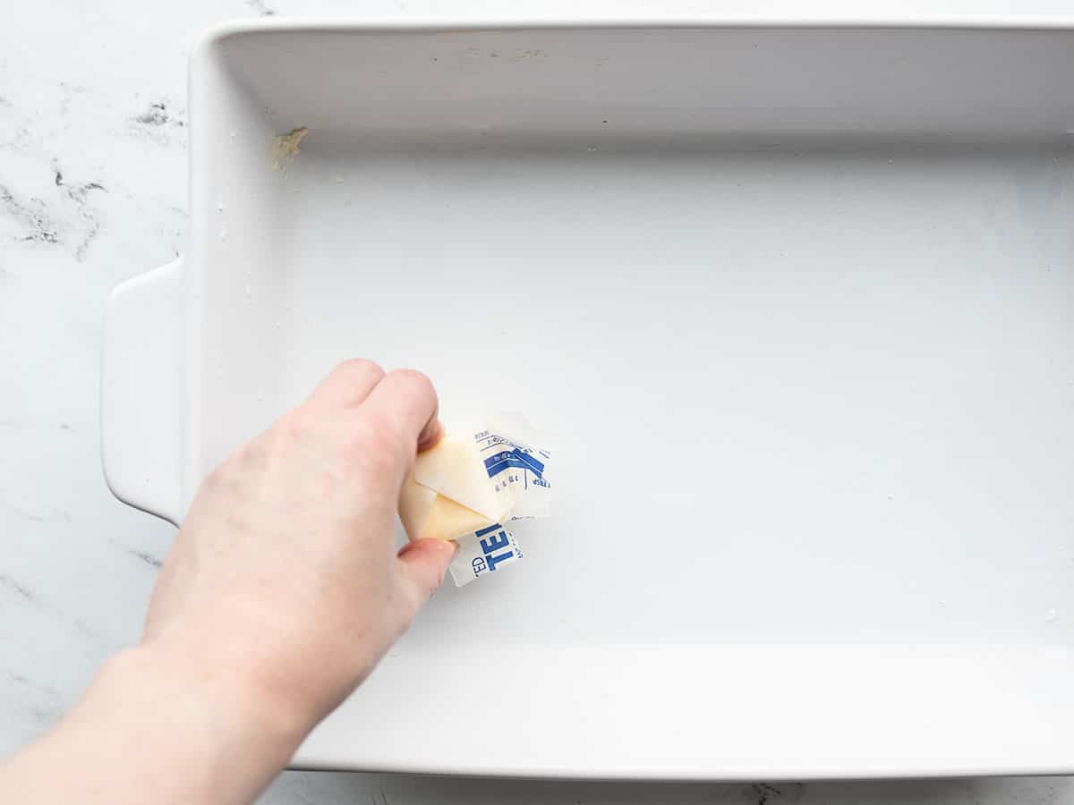 casserole dish being buttered