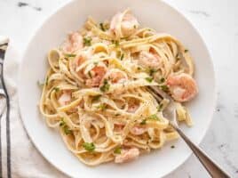 Shrimp alfredo pasta in a bowl with a fork on the side