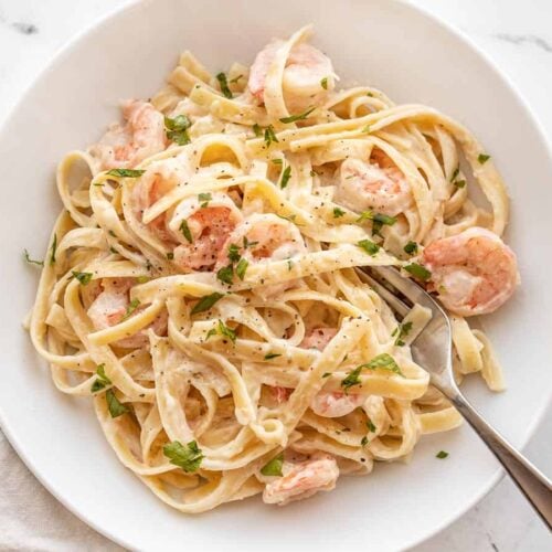 Shrimp alfredo pasta in a bowl with a fork on the side