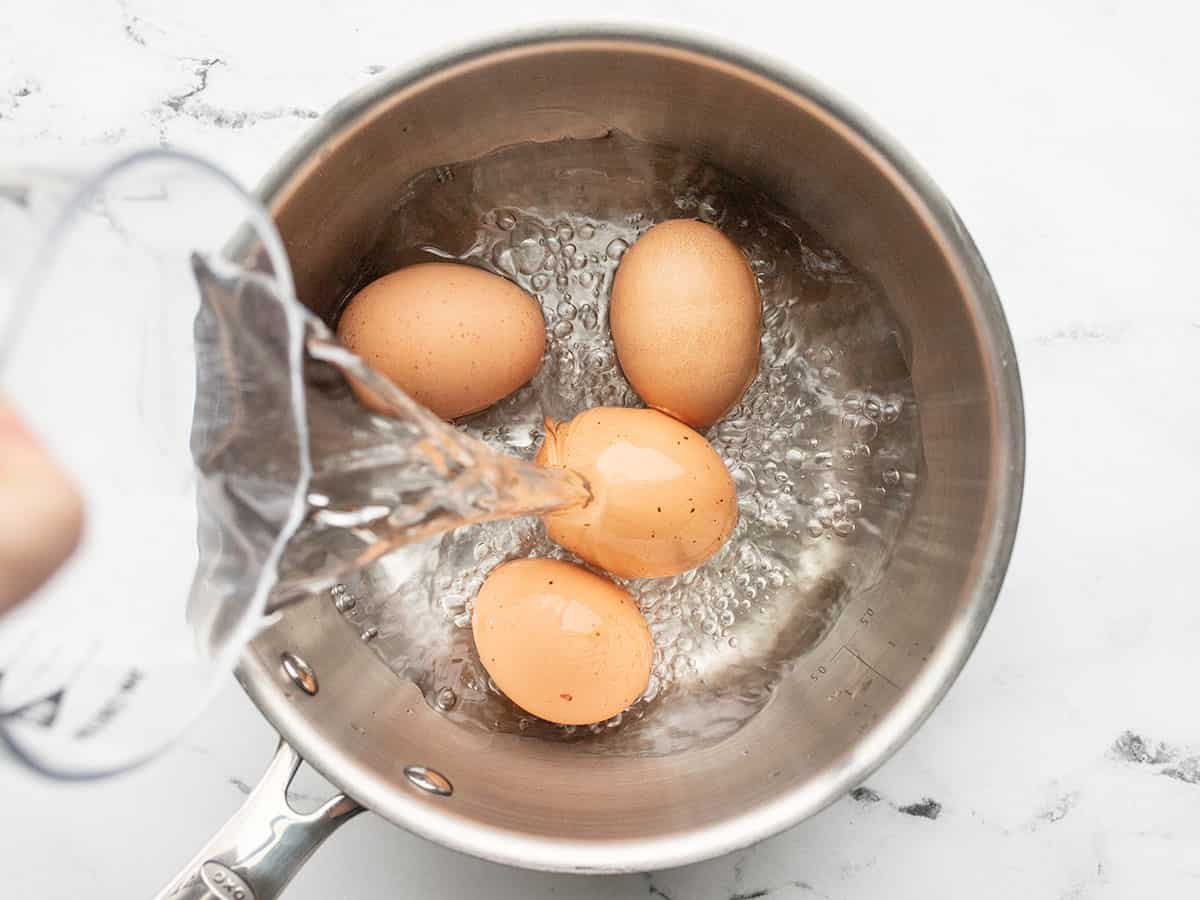 Water being poured into a pot with eggs