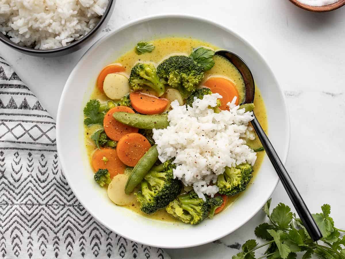 A bowl of vegetable curry topped with a scoop of rice