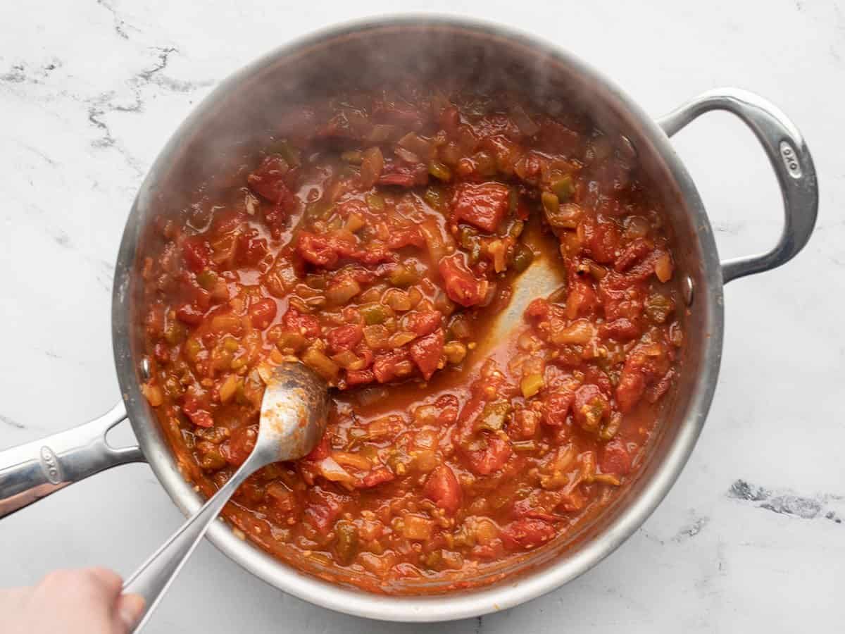 Simmered salsa in the skillet, a spoon dragging to show thickness.