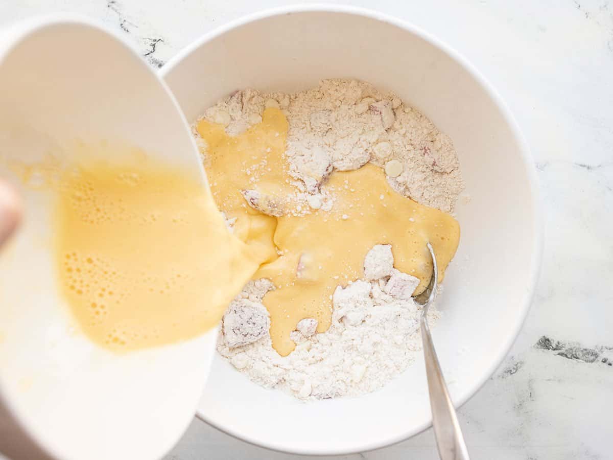 wet ingredients being poured into the bowl of dry ingredients