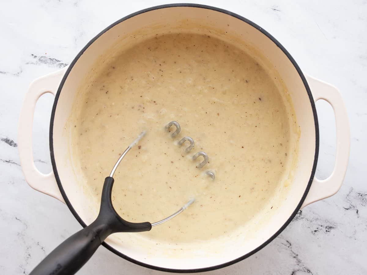 Potato masher in the pot of soup. 