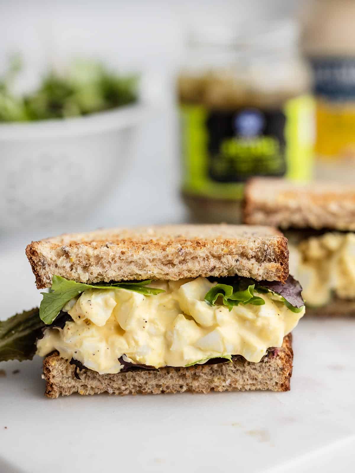 An egg salad sandwich cut in half facing the camera