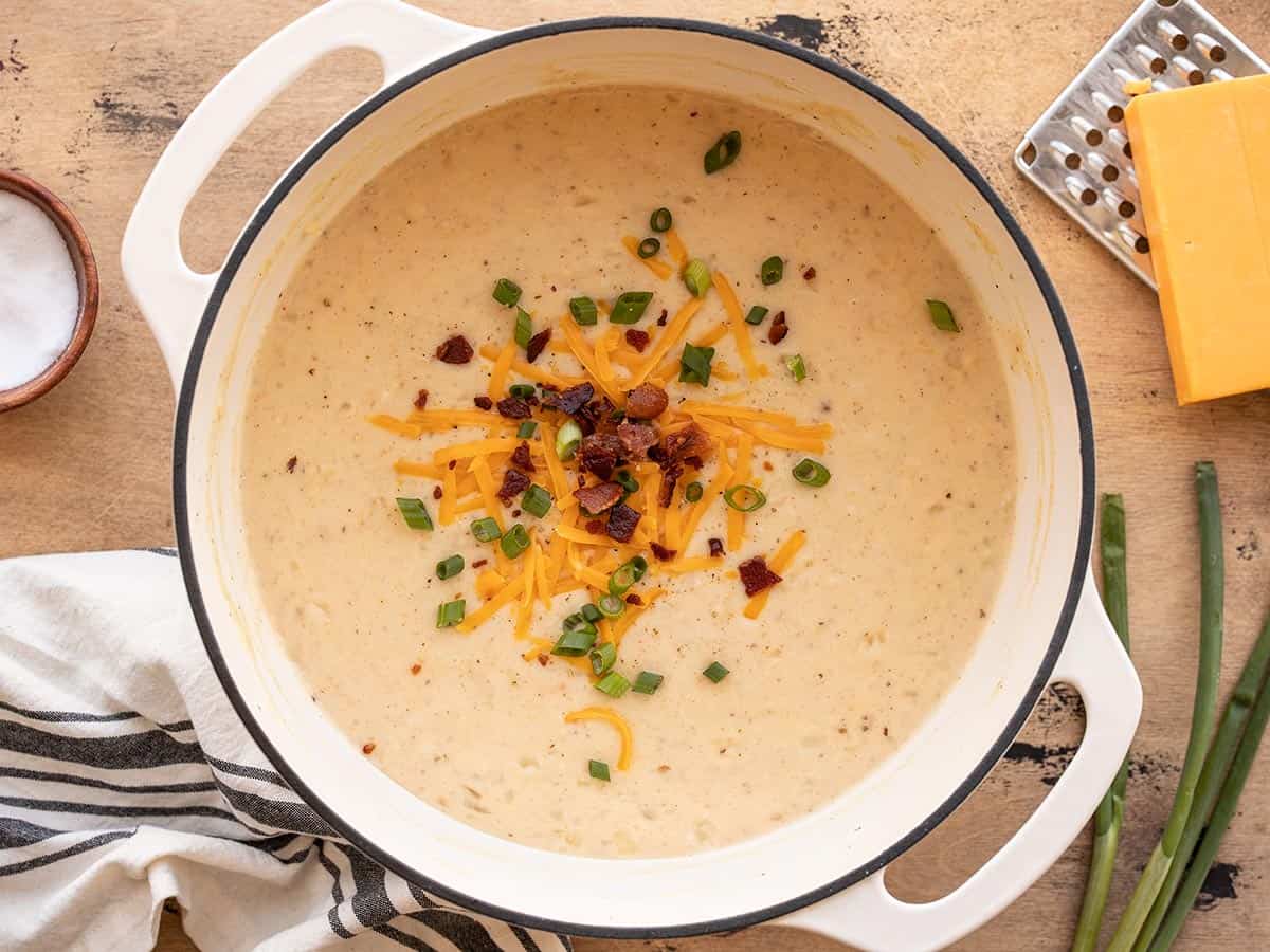 A pot of potato soup with toppings added.