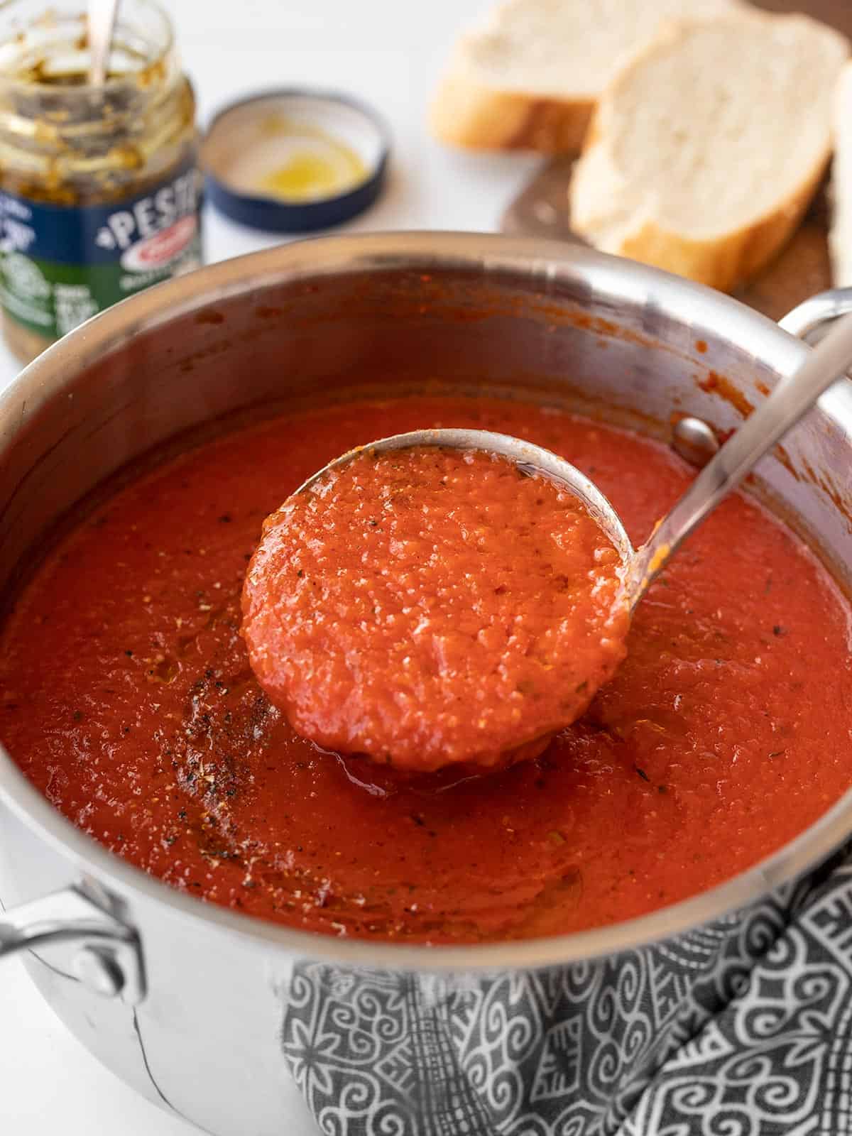 A ladle full of roasted red pepper soup being lifted from the pot.