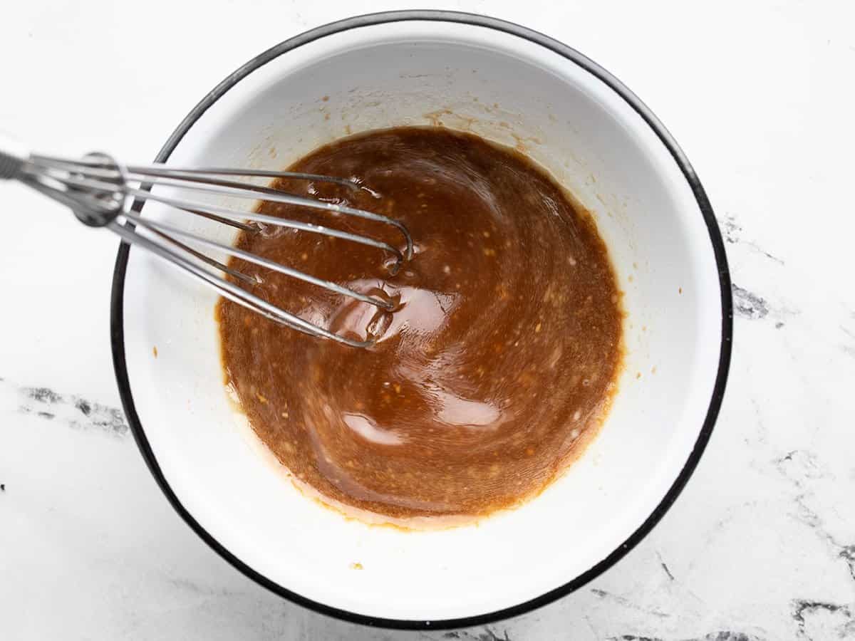 stir fry sauce being whisked in a white bowl