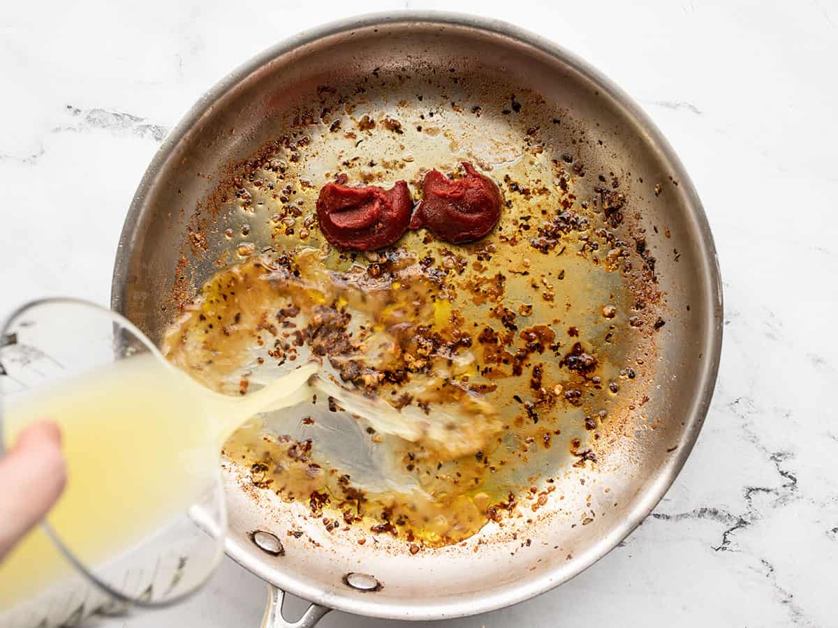 Pan sauce ingredients being added to the skillet.